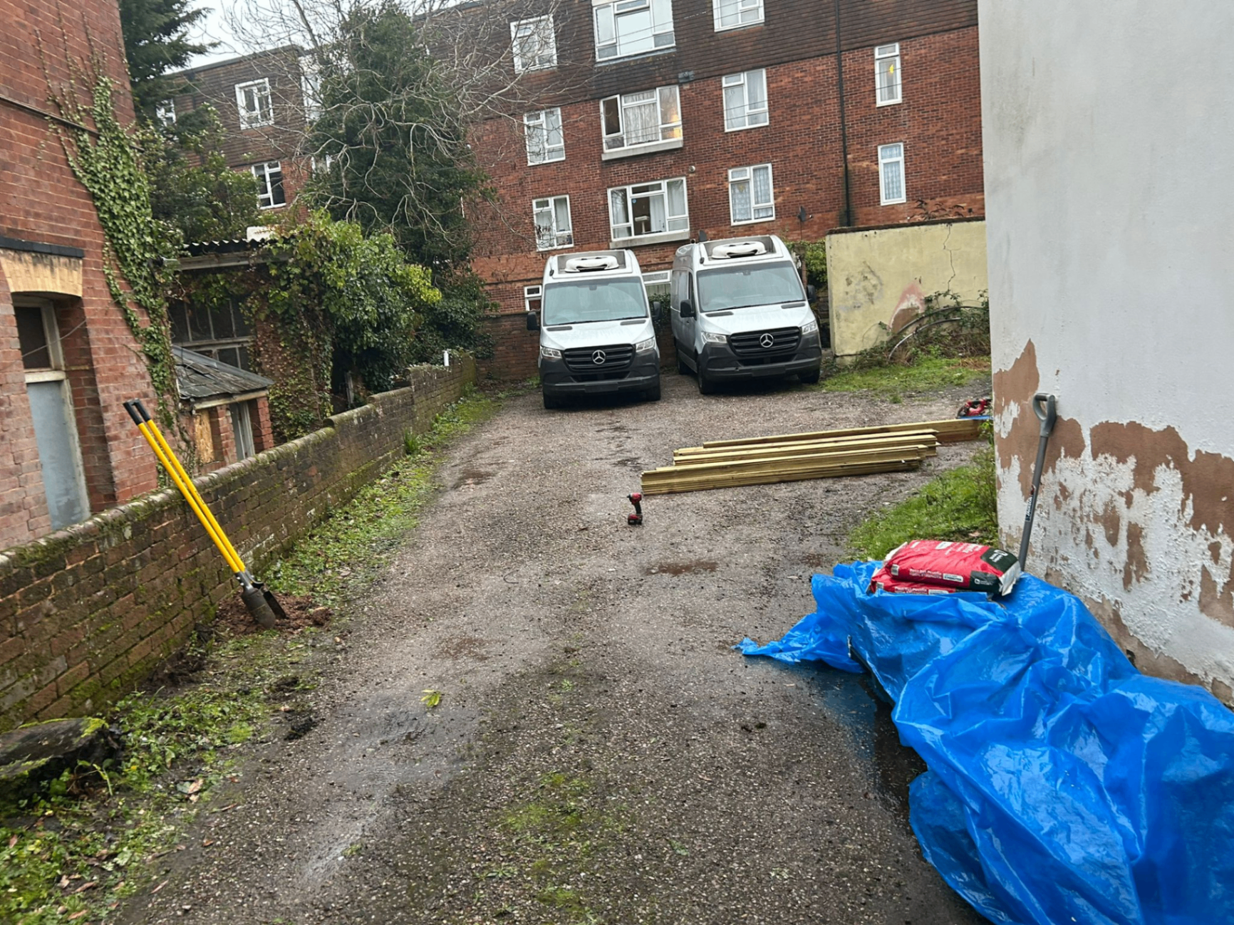 Open exposed side driveway with parked vans before AJW Carpentry installed a timber gate in Exeter