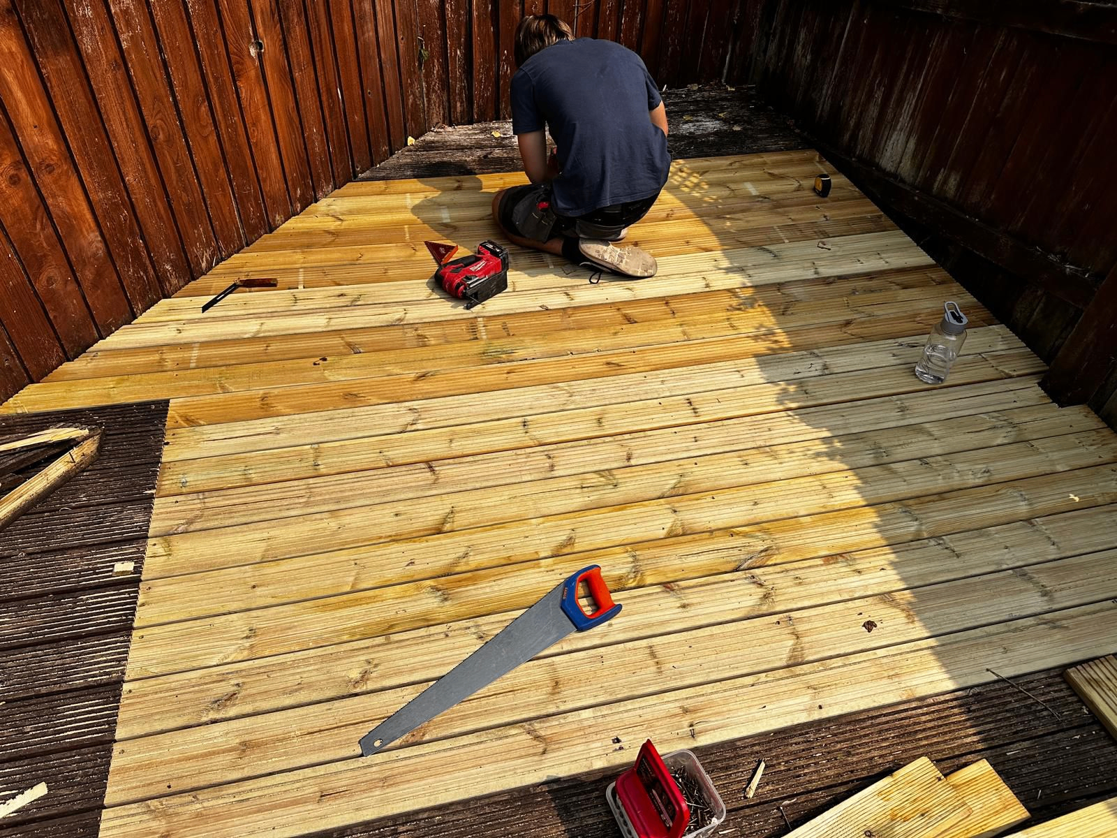 New treated timber decking boards laid over a stripped-out sub-frame in a Sidmouth garden by AJW Carpentry