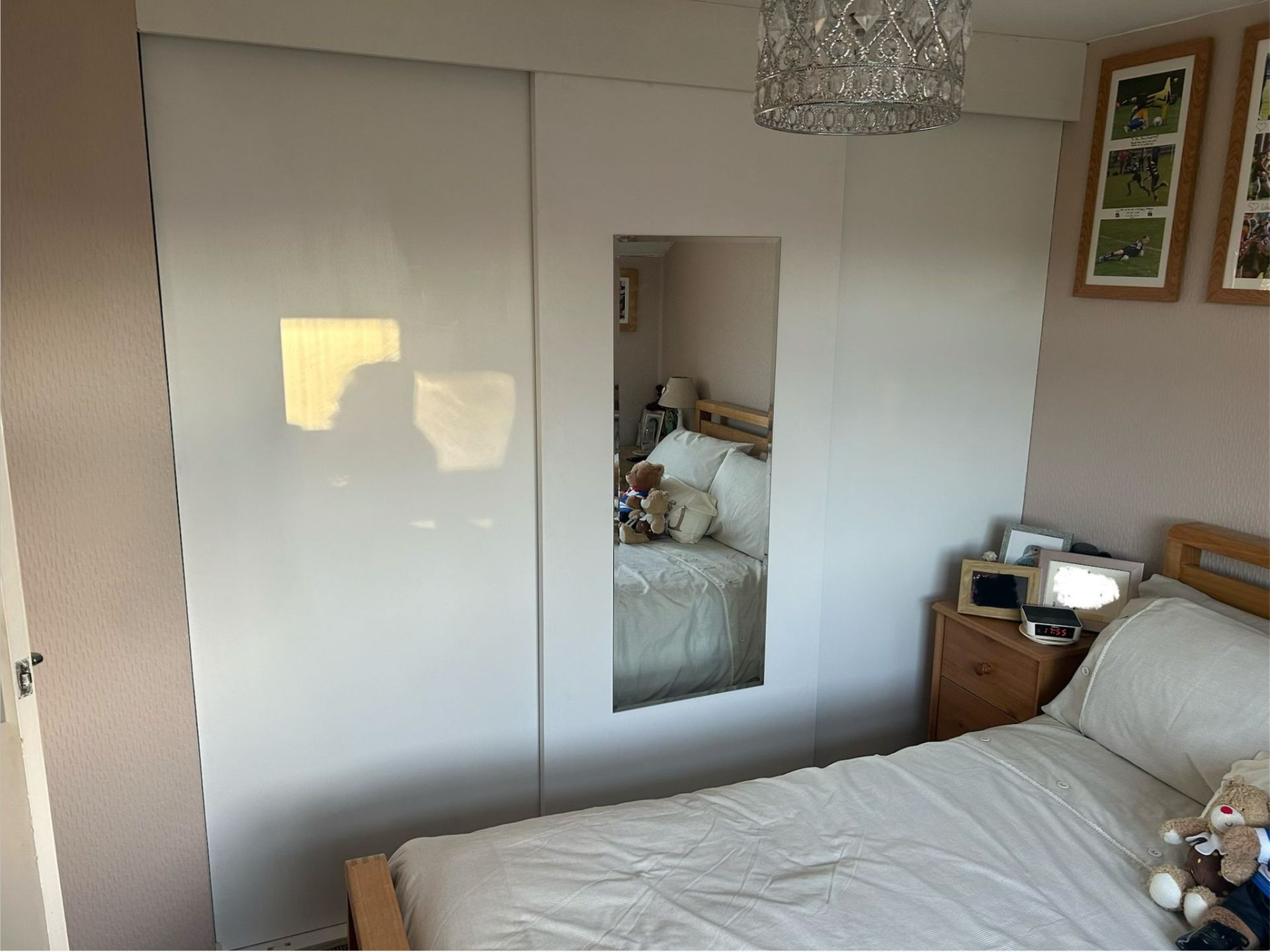 Newly fitted white sliding wardrobe doors with mirror in a Sidmouth bedroom by AJW Carpentry