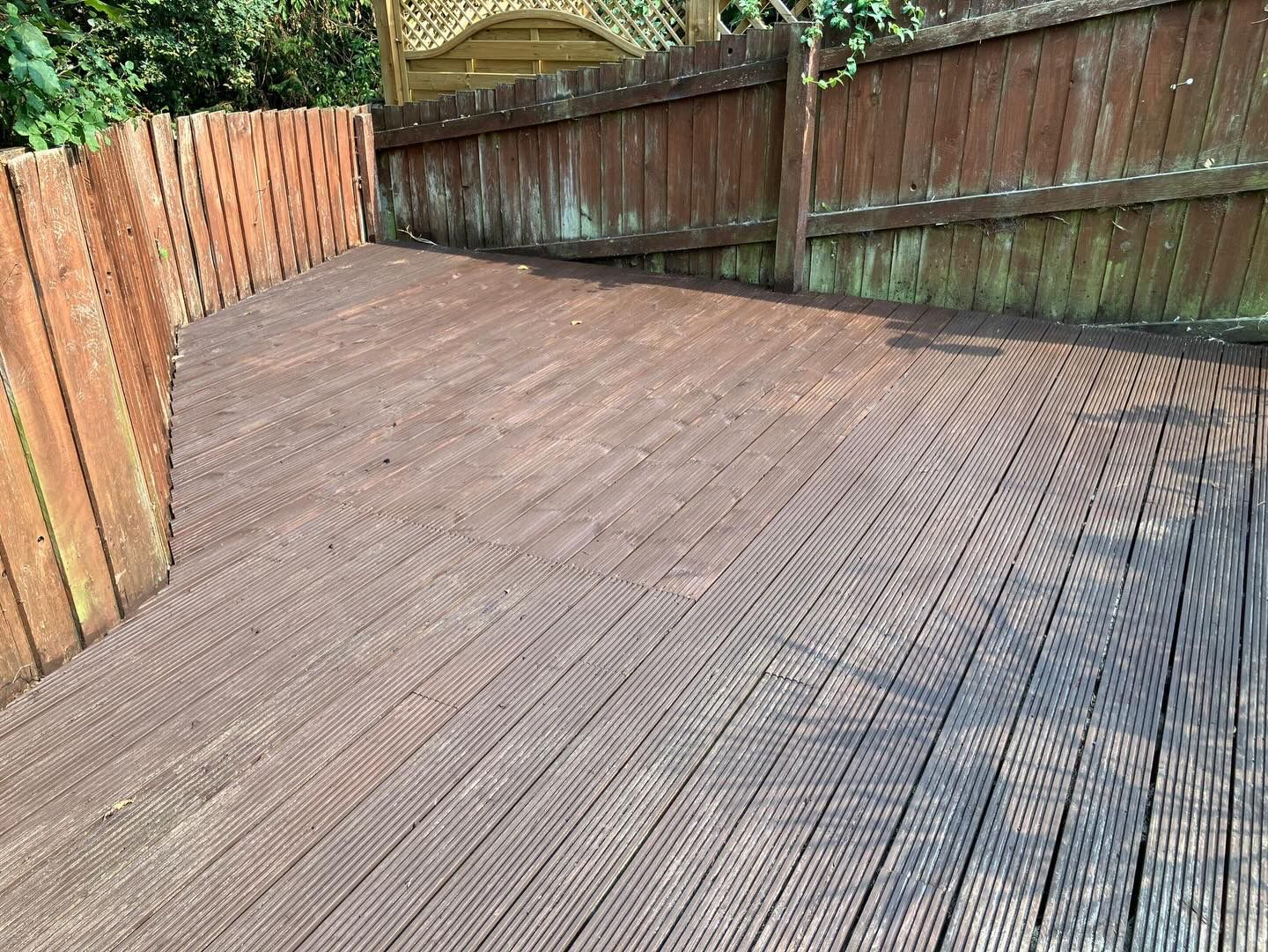 Tired, weather-worn dark timber decking in a Sidmouth garden before rebuild by AJW Carpentry